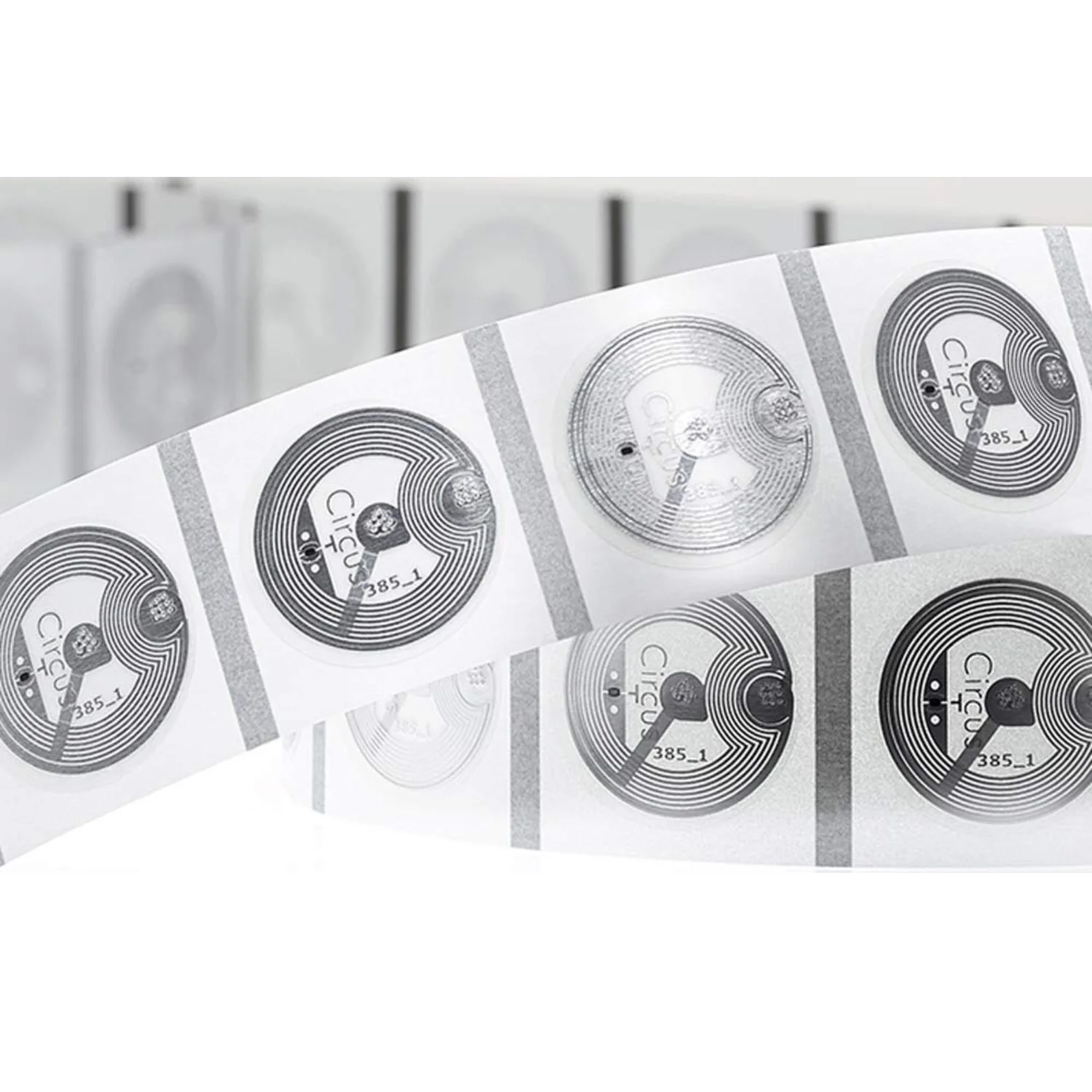 A roll of transparent circular NFC stickers with visible circuitry and printed text.