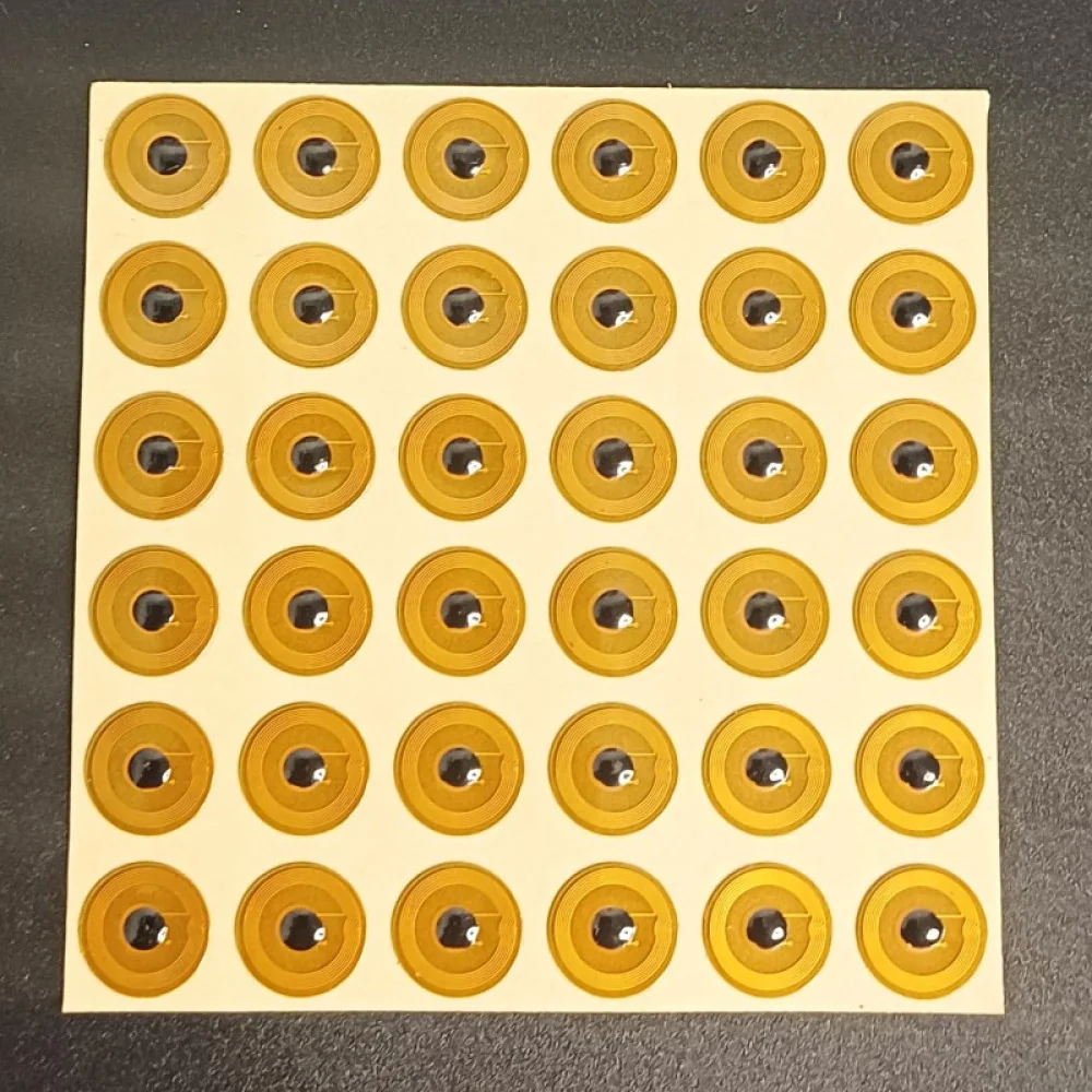 Multiple small, round, yellow NFC stickers with black centers arranged in a grid on a white backing sheet.