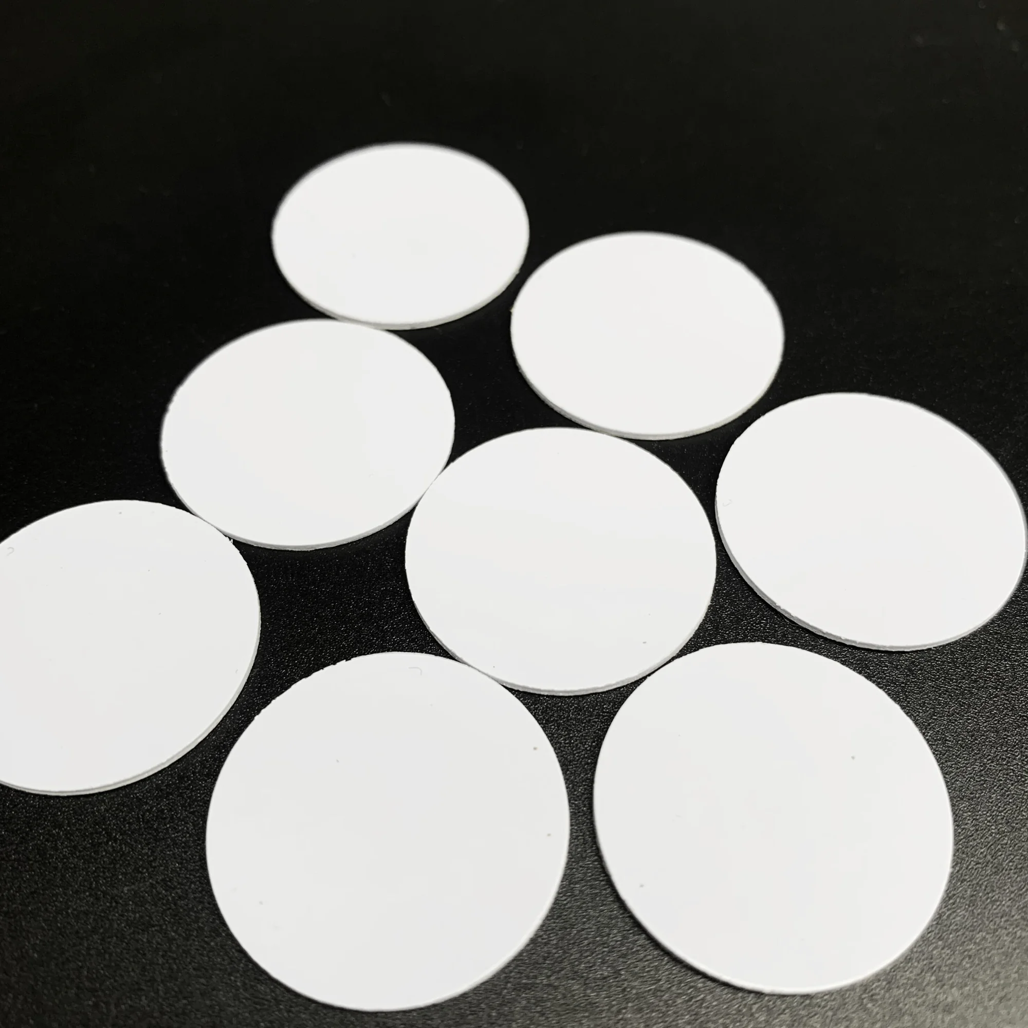 White circular NFC coin tags arranged on a black surface.